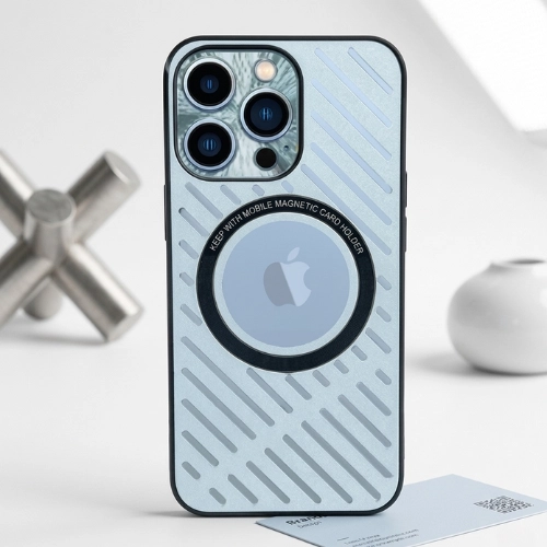 Silver metal MagSafe iPhone case with circular magnetic ring, diagonal heat-dissipation grooves, and a black TPU frame, shown in a clean minimalist setting with metallic decor objects